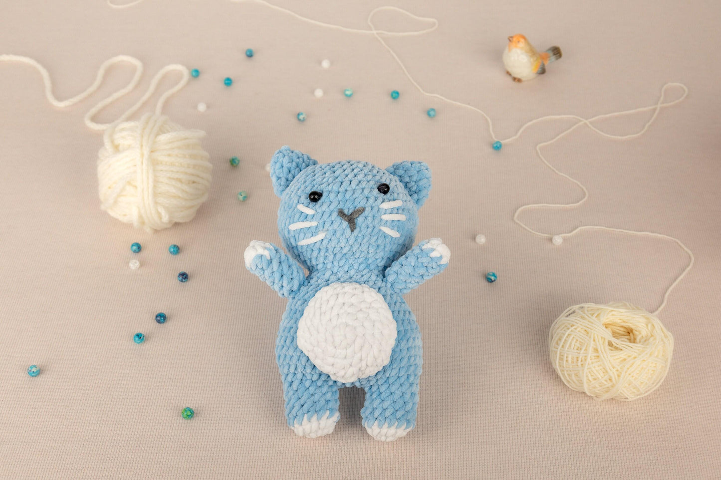 a crocheted cat next to a ball of yarn