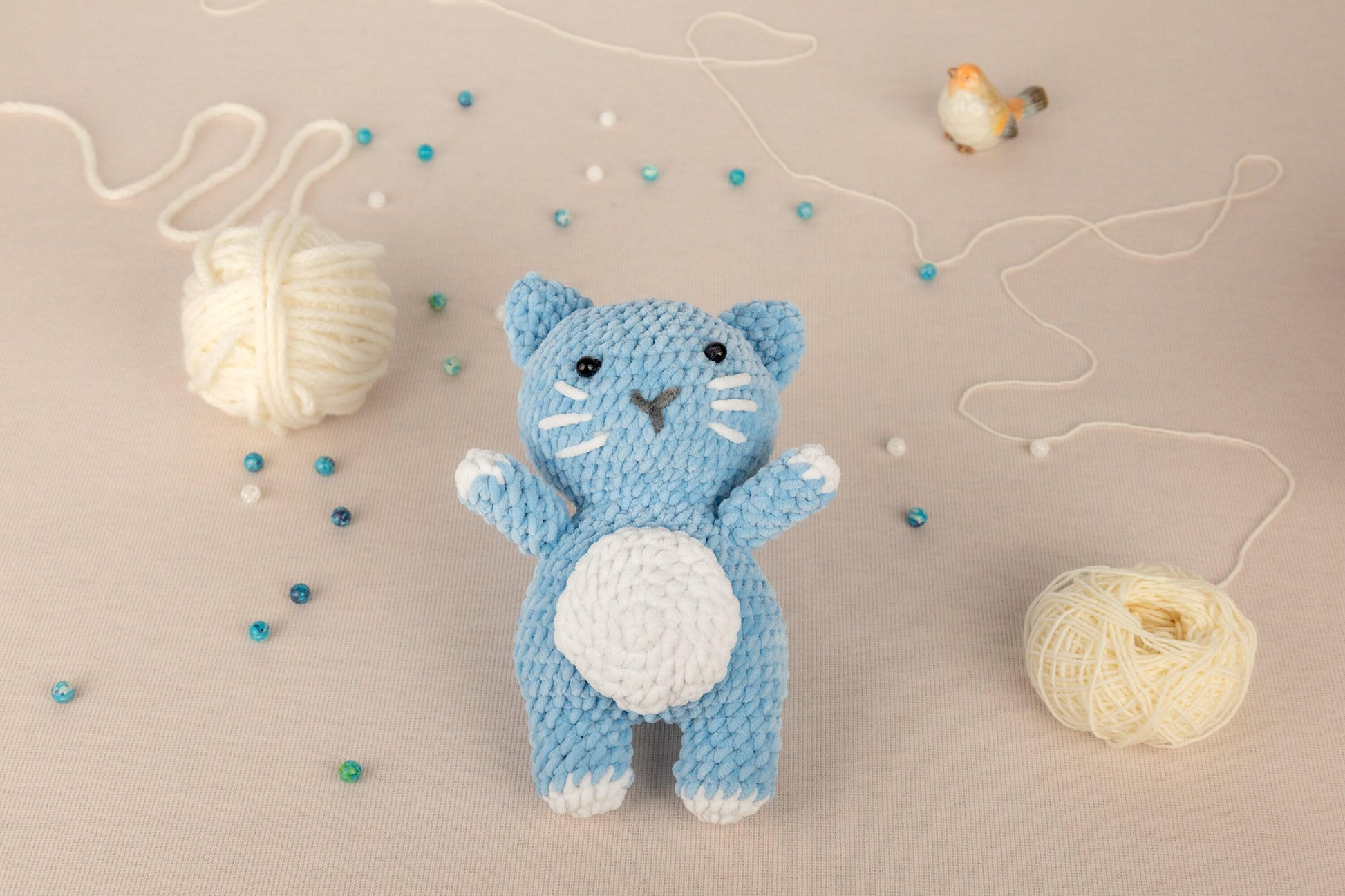 a crocheted cat next to a ball of yarn