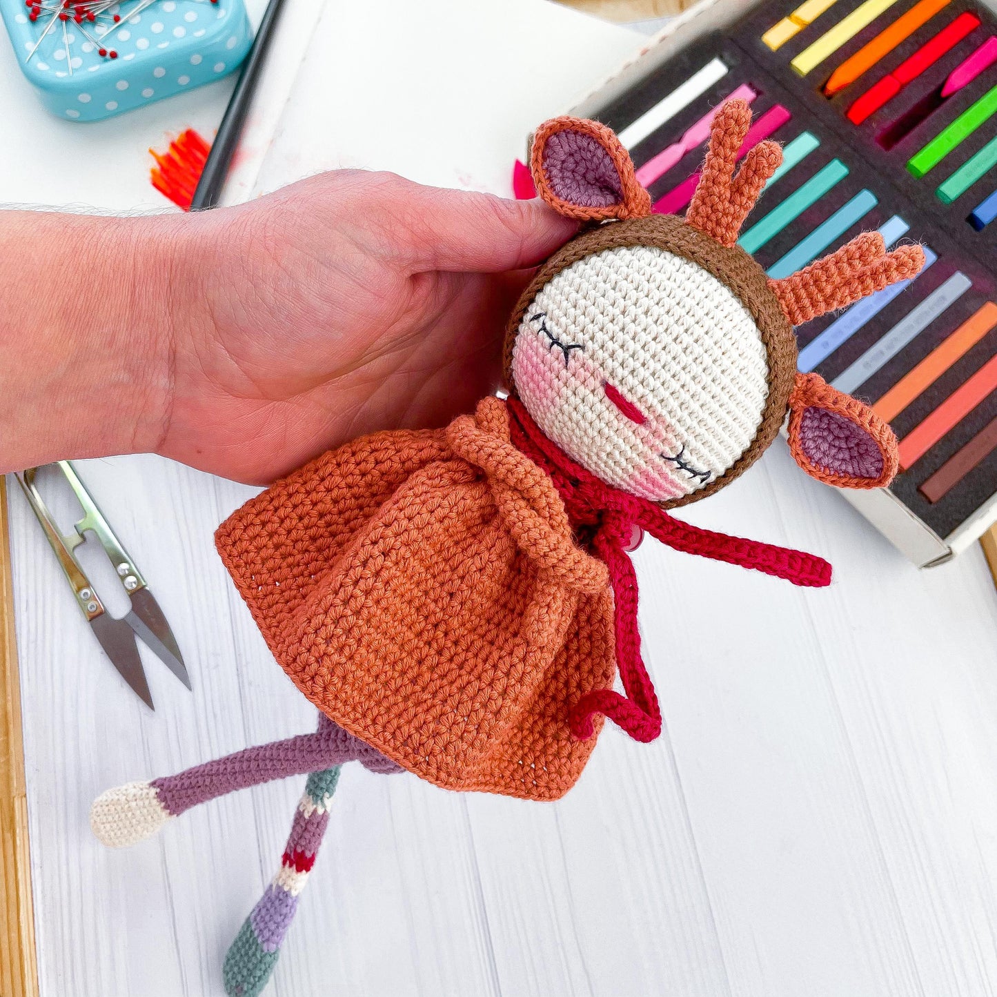a crocheted doll being held by a hand