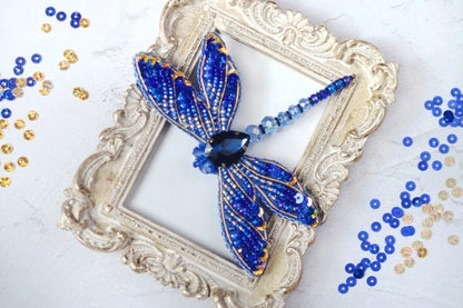 a blue dragonfly brooch sitting on top of a picture frame