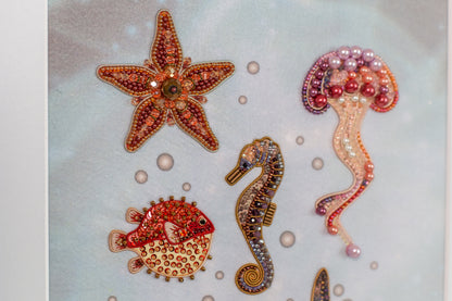 a collection of colorful, intricately designed sea creatures, including a starfish, a pufferfish, a seahorse, and a jellyfish, all adorned with sparkling embellishments.