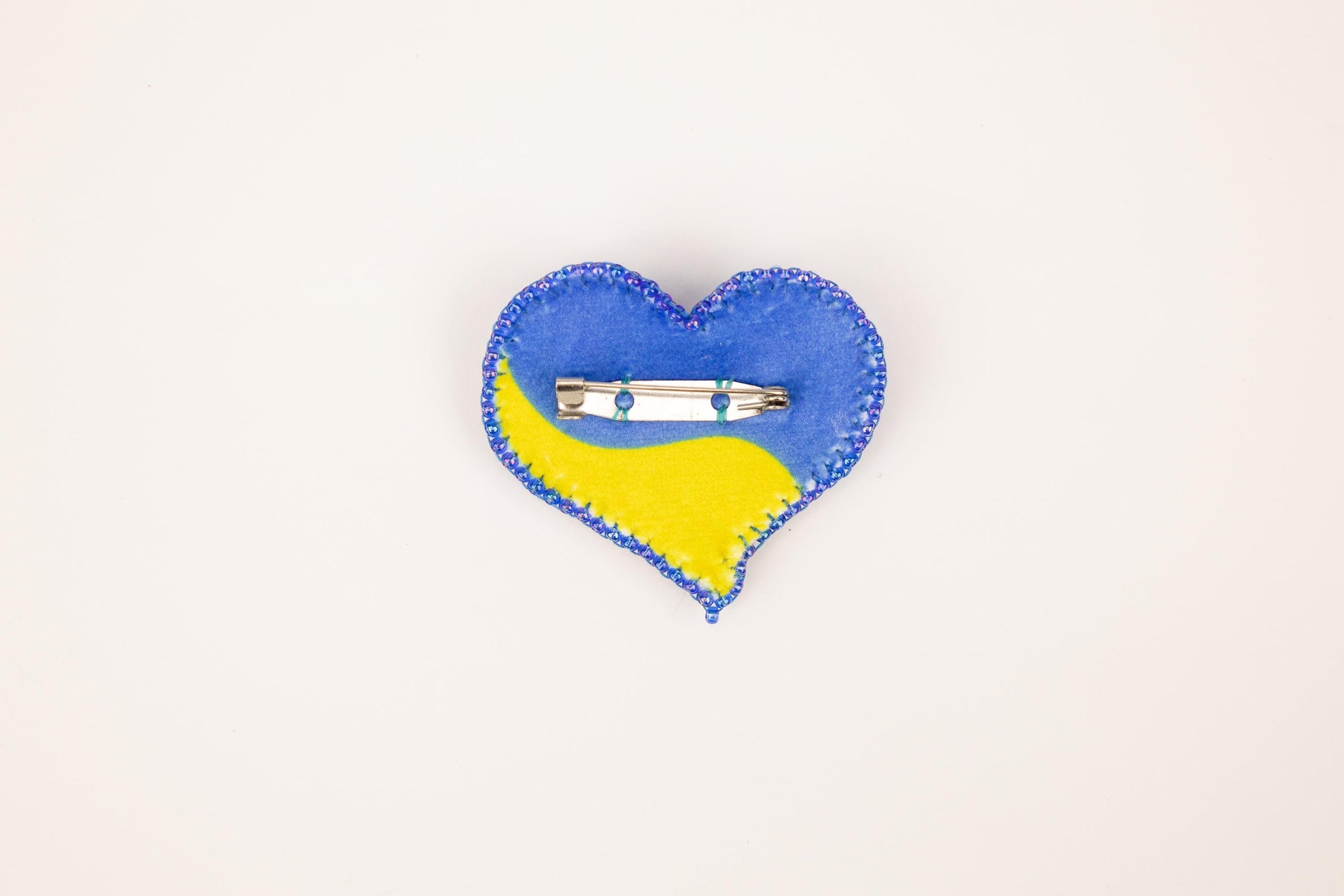 a blue and yellow heart shaped pin on a white background
