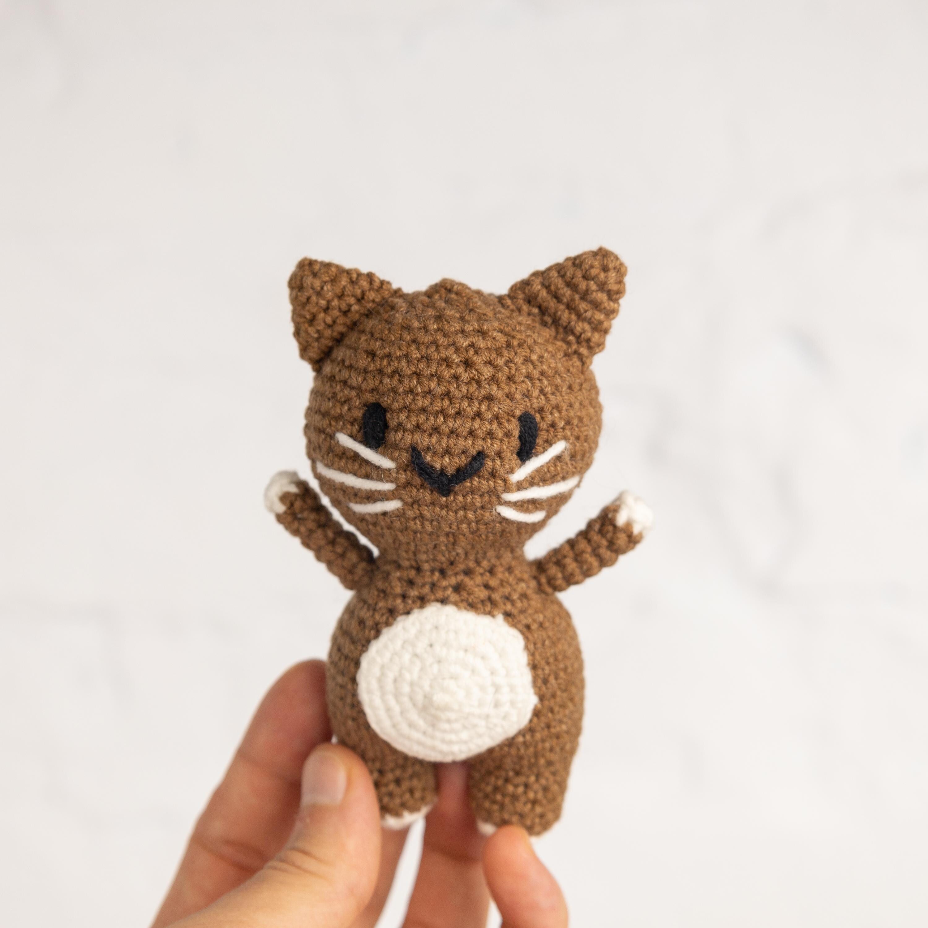 a hand holding a small crocheted cat