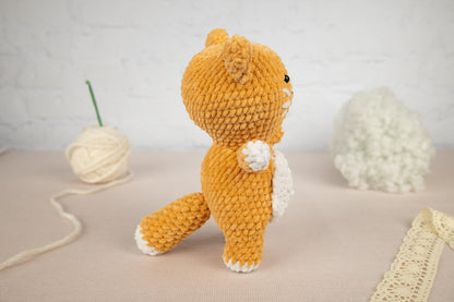 a hand holding a small crocheted cat