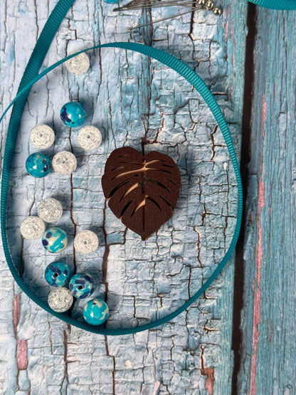 a blue and white bag with beads and a leaf on it