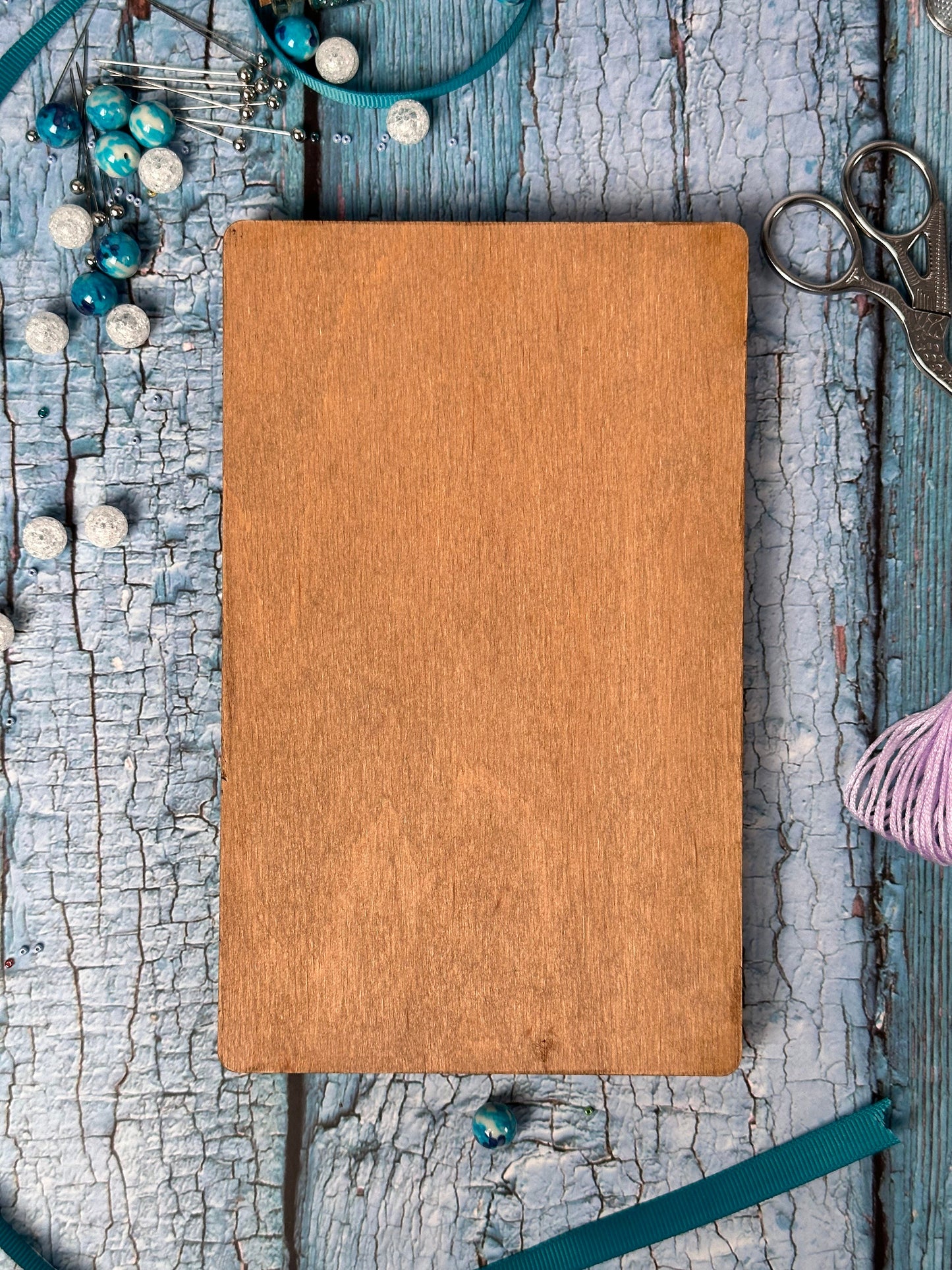 a wooden board surrounded by beads and a pair of scissors