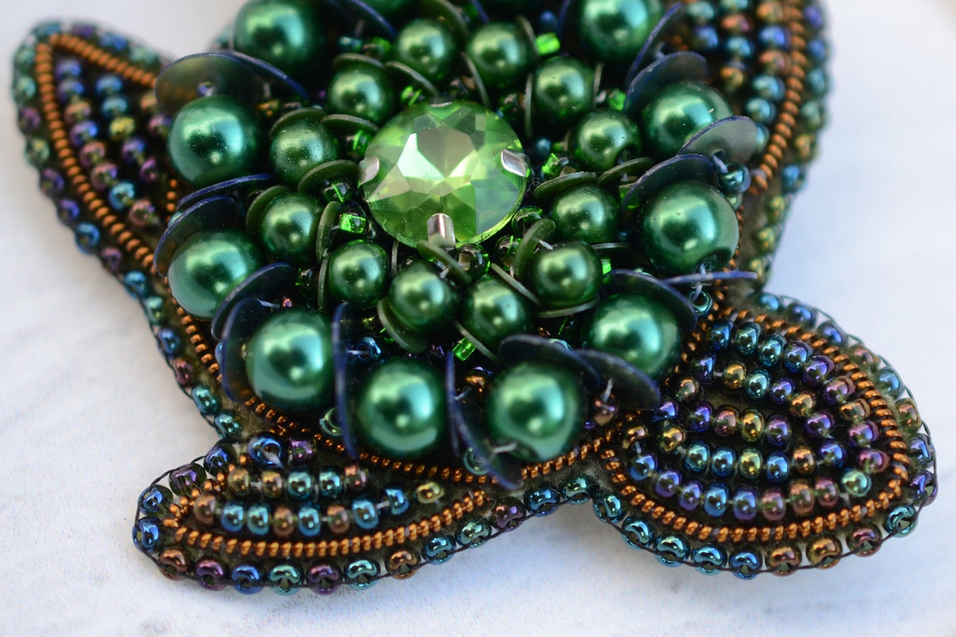 a brooch with pearls and a green bead