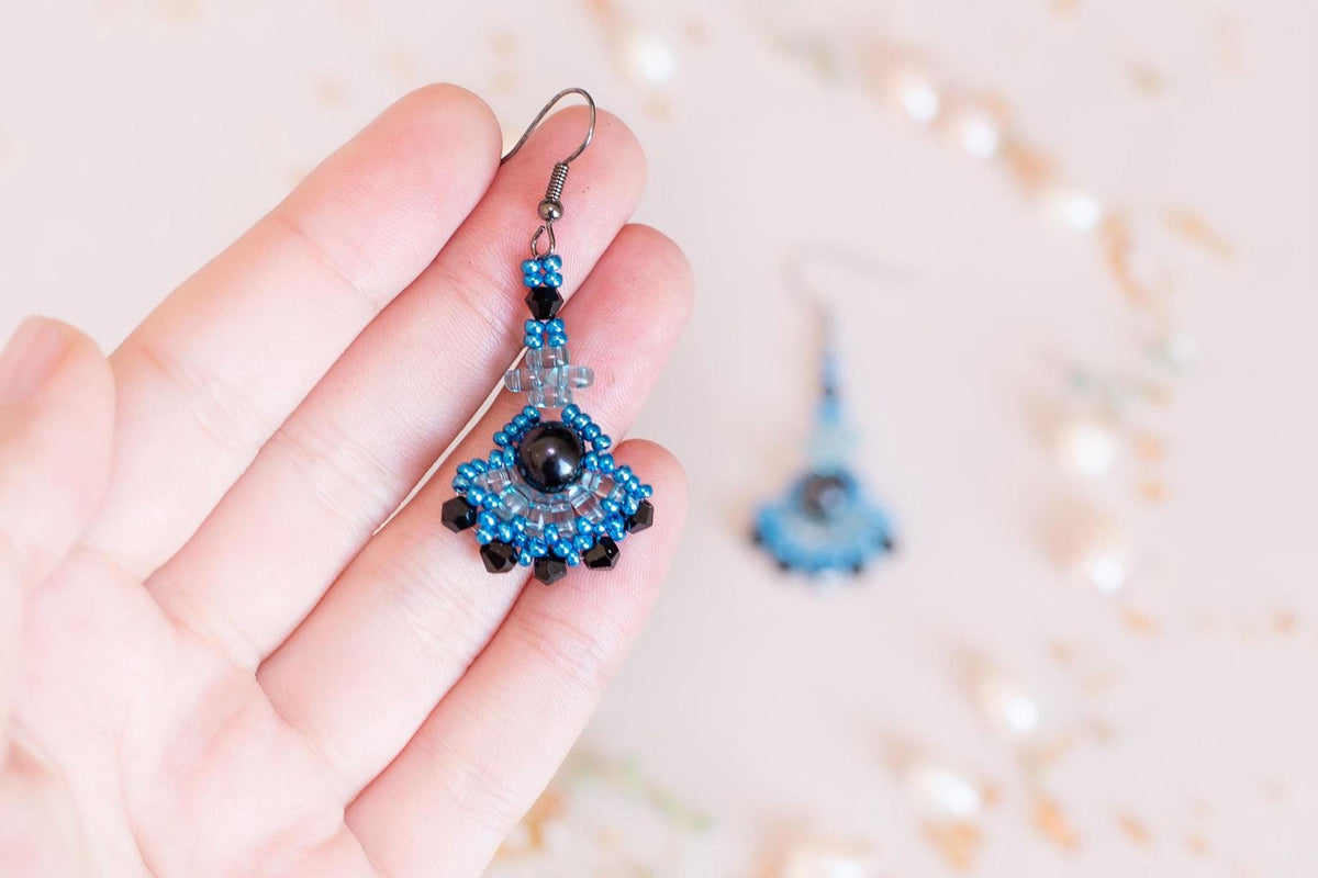 a person holding a pair of earrings in their hand