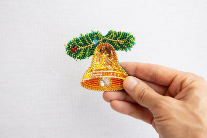 a hand holding a beaded bell ornament
