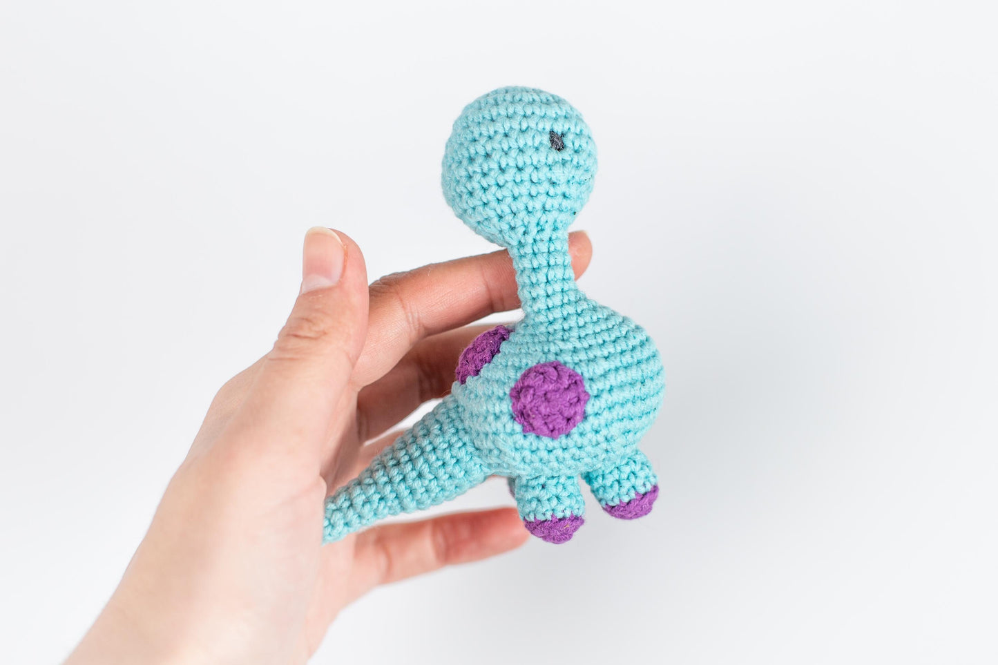 a hand holding a small crocheted stuffed animal