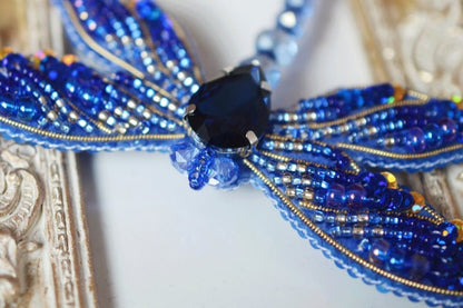 a blue beaded necklace with a black diamond
