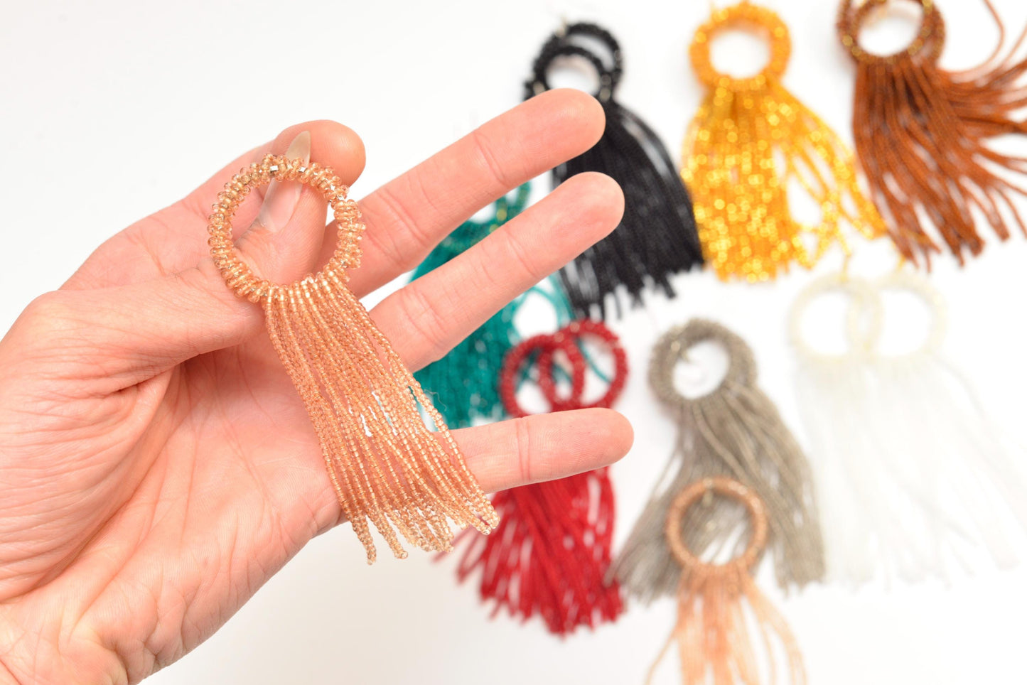 a hand holding a ring with tassels on it