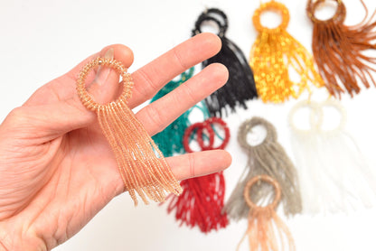 a hand holding a ring with tassels on it