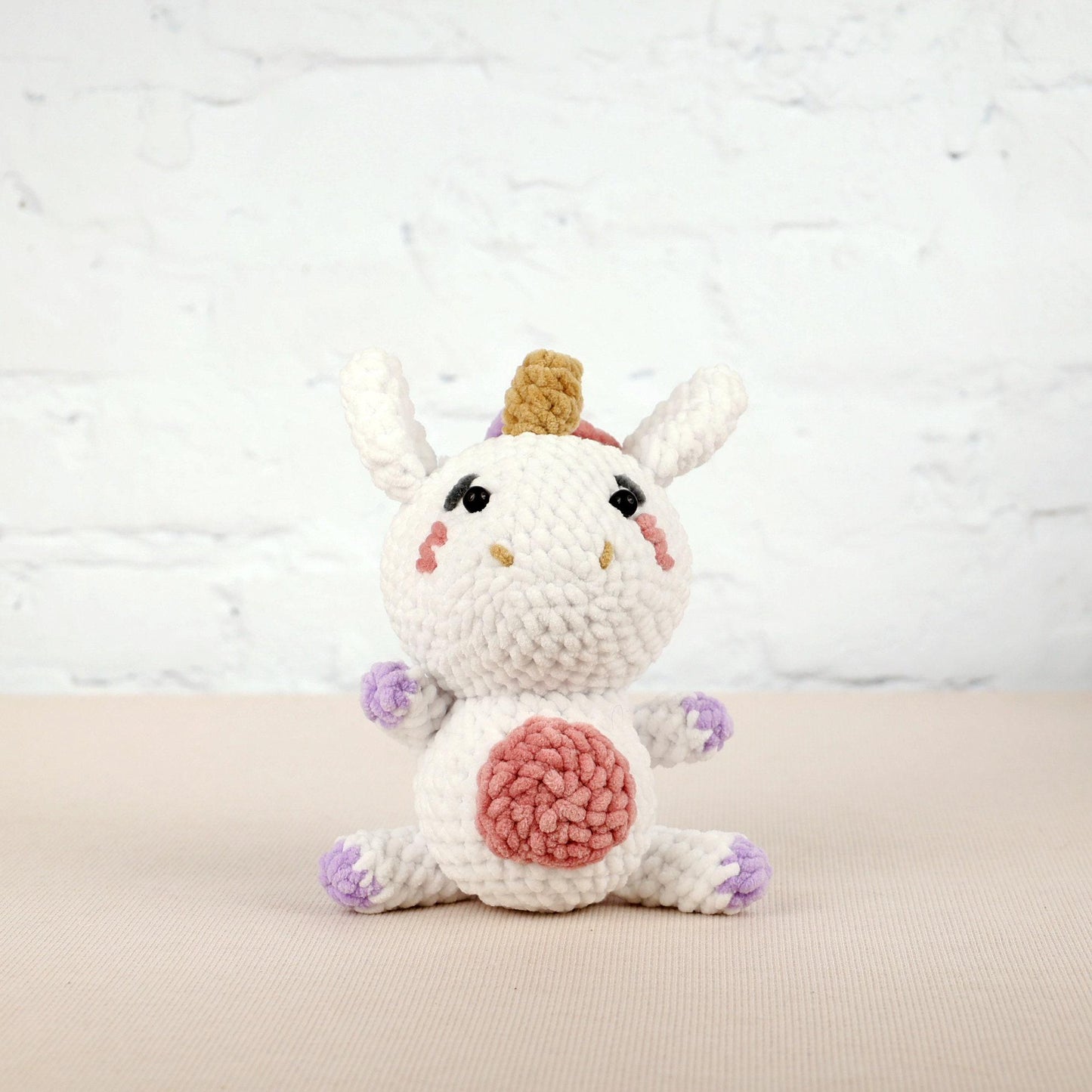 a crocheted white unicorn with a pink heart