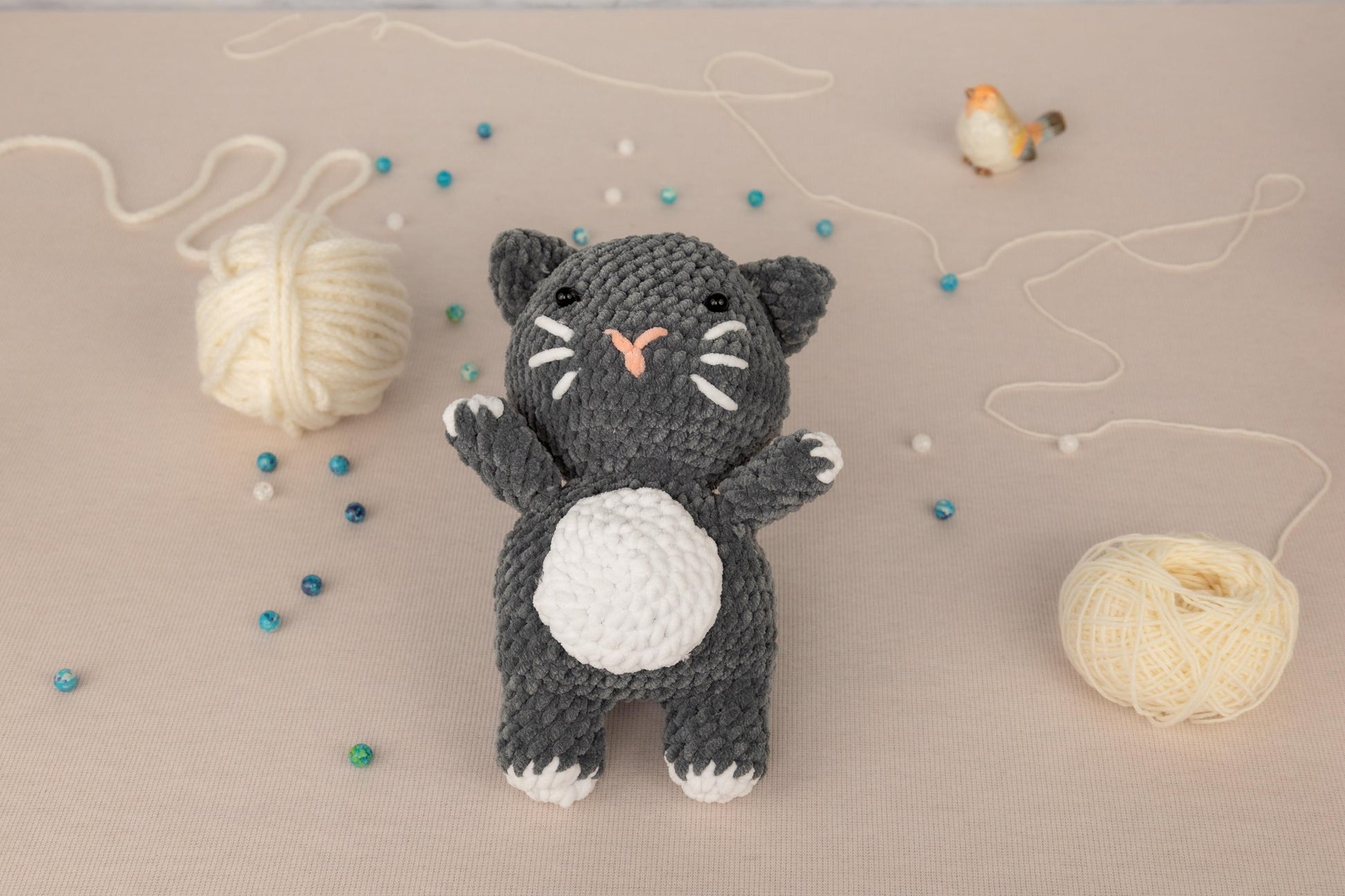 a crocheted black and white cat next to a ball of yarn