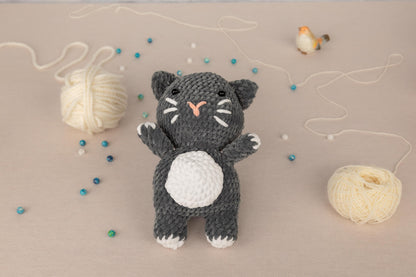 a crocheted black and white cat next to a ball of yarn