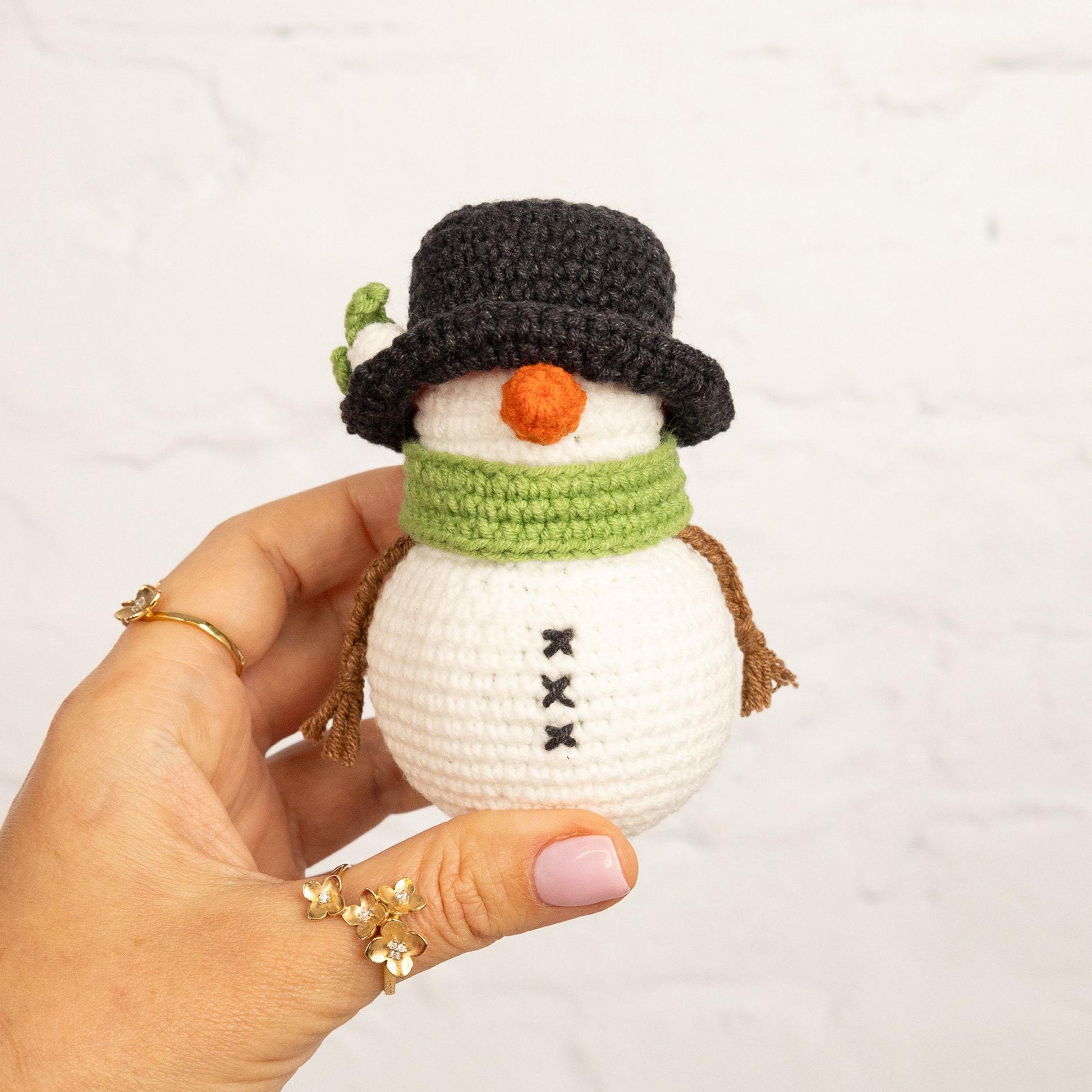 a hand holding a crocheted snowman ornament