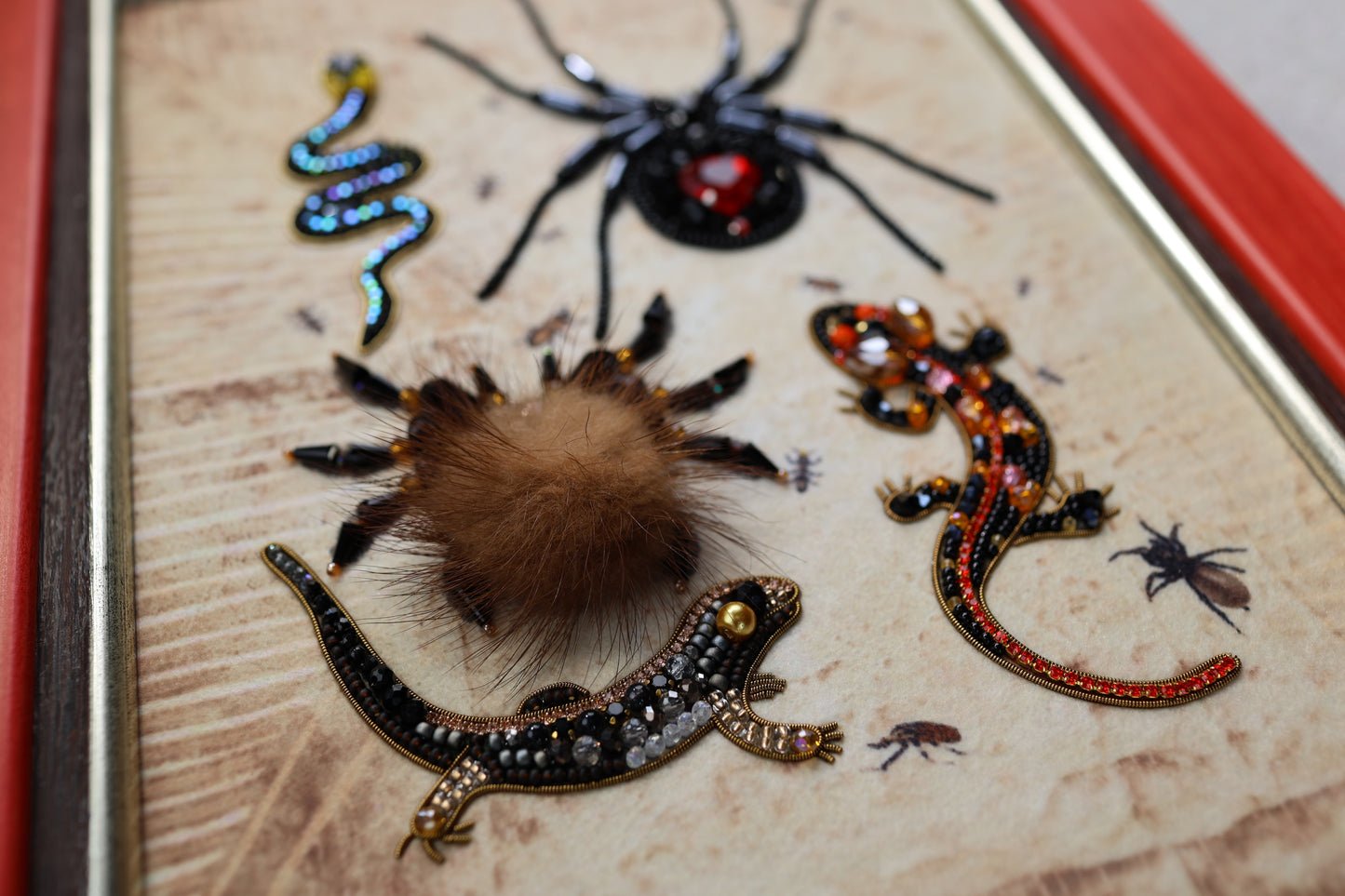 a close-up of various insects and animals, including a spider, a lizard, and a tarantula, all intricately detailed and adorned with colorful beads and embroidery.