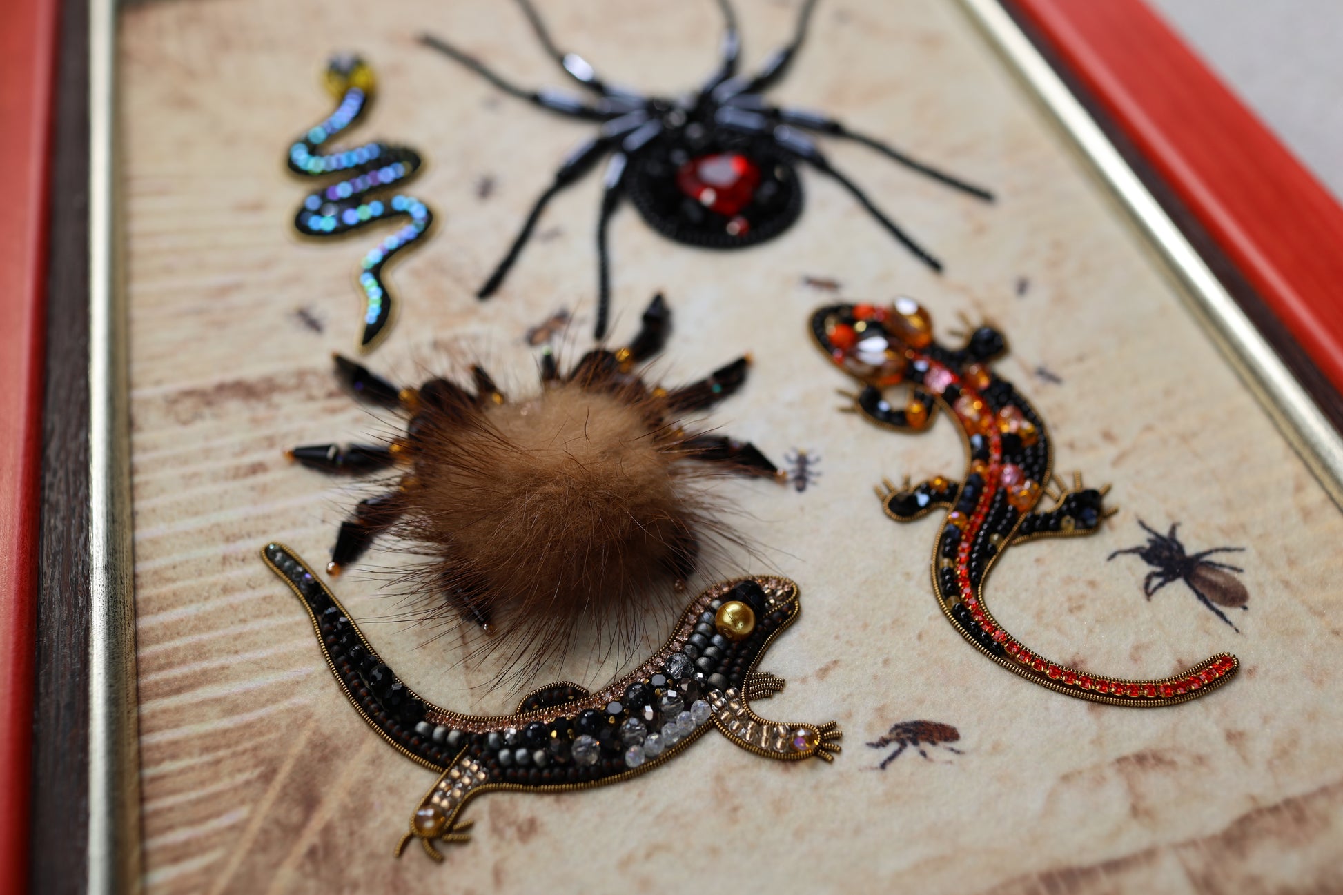 a close-up of various insects and animals, including a spider, a lizard, and a tarantula, all intricately detailed and adorned with colorful beads and embroidery.
