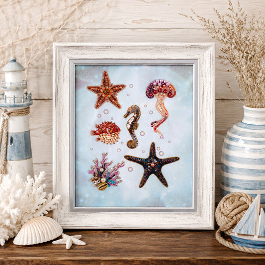 A framed collage of various marine life, including a starfish, jellyfish, and seahorse, is displayed on a wooden surface.