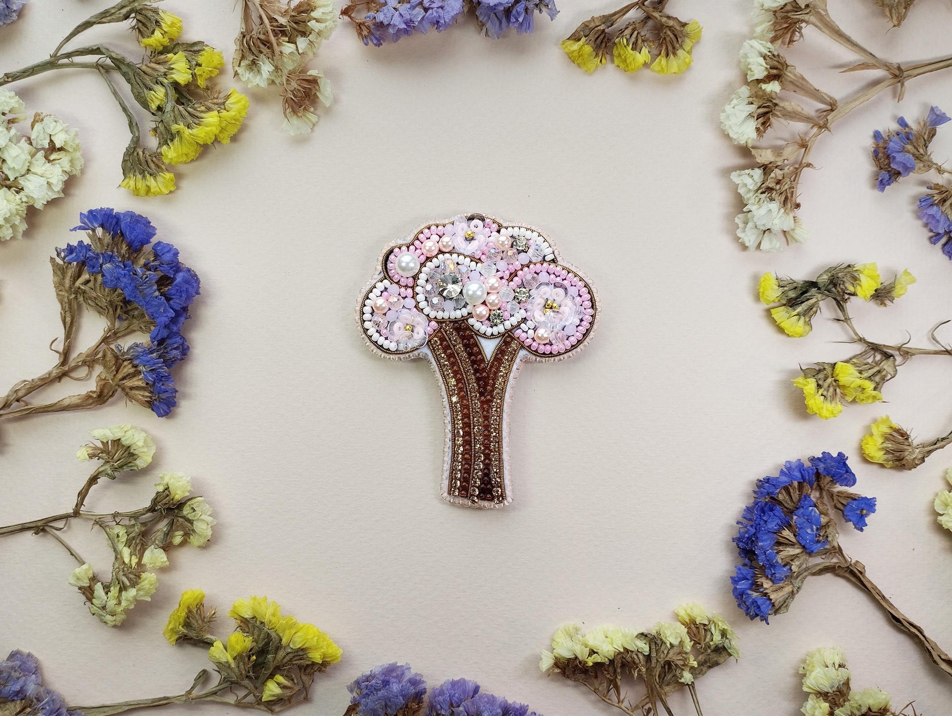a brooch with a tree on it surrounded by flowers