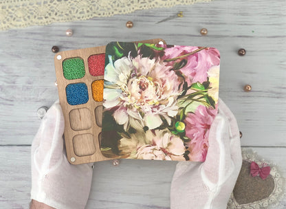 a person&#39;s hands holding a palette with flowers on it