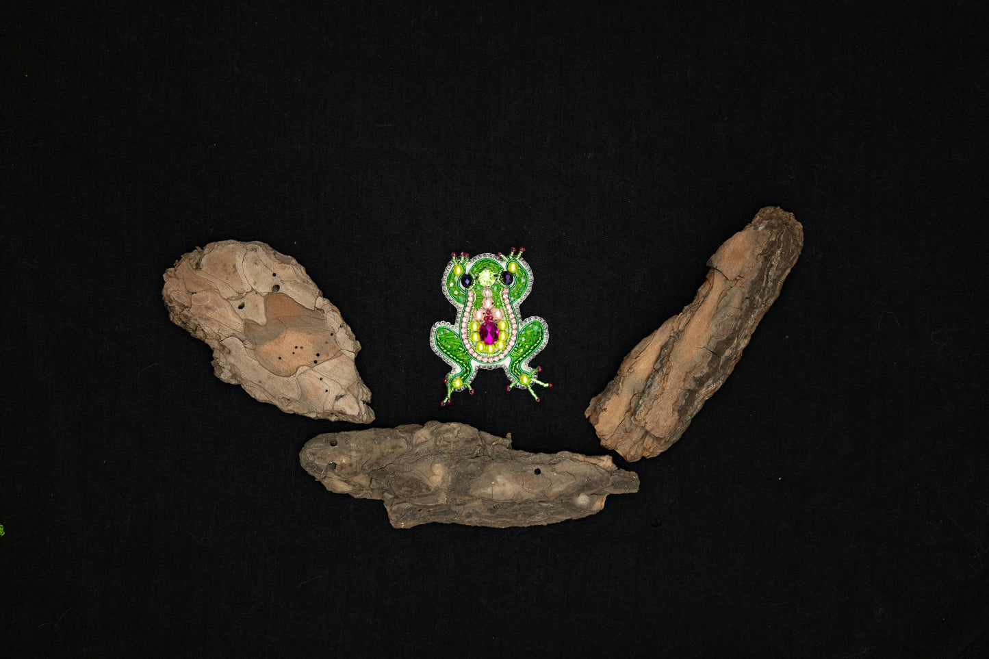 a green frog sitting on top of a piece of wood