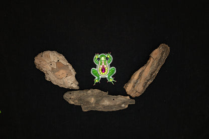 a green frog sitting on top of a piece of wood