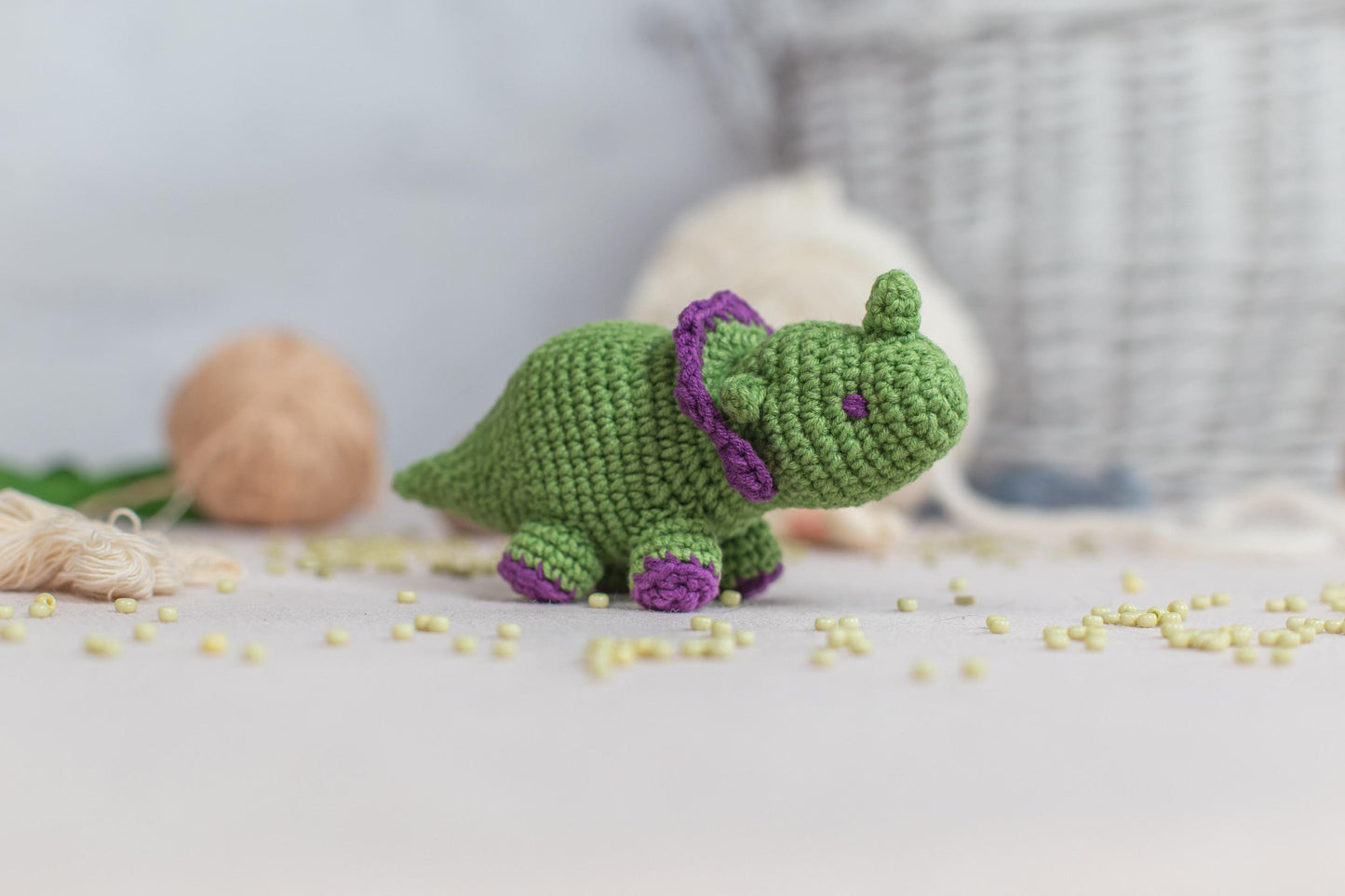 a green crocheted stuffed animal sitting on a bed