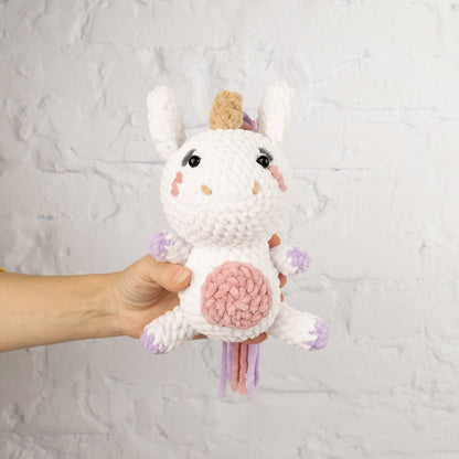 a hand holding a small stuffed animal unicorn