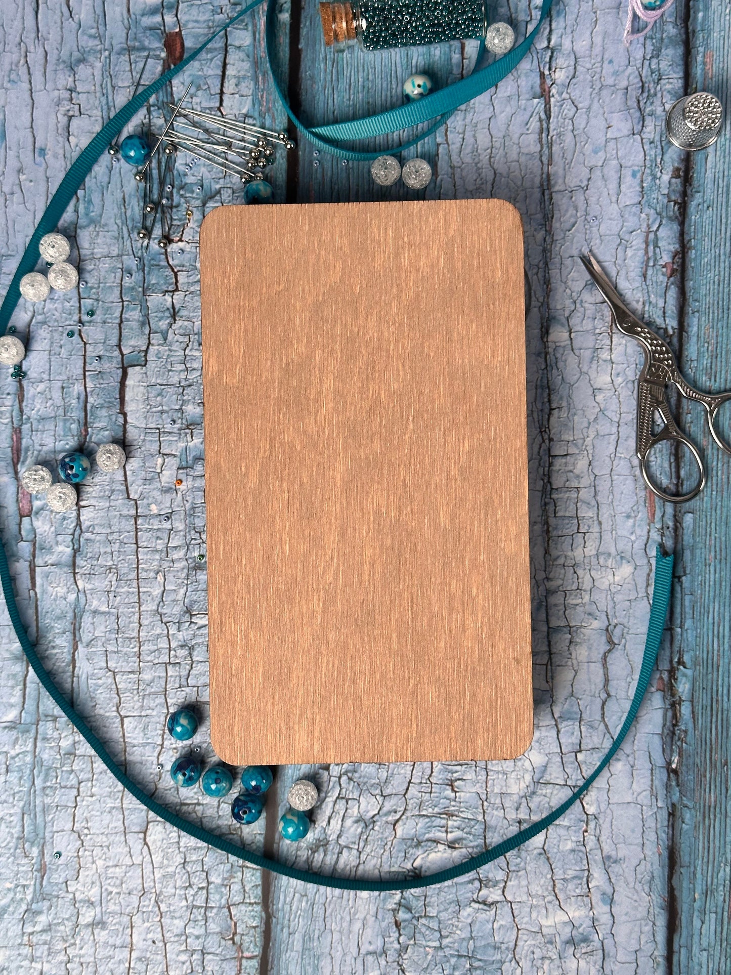 a wooden board surrounded by beads and a pair of scissors