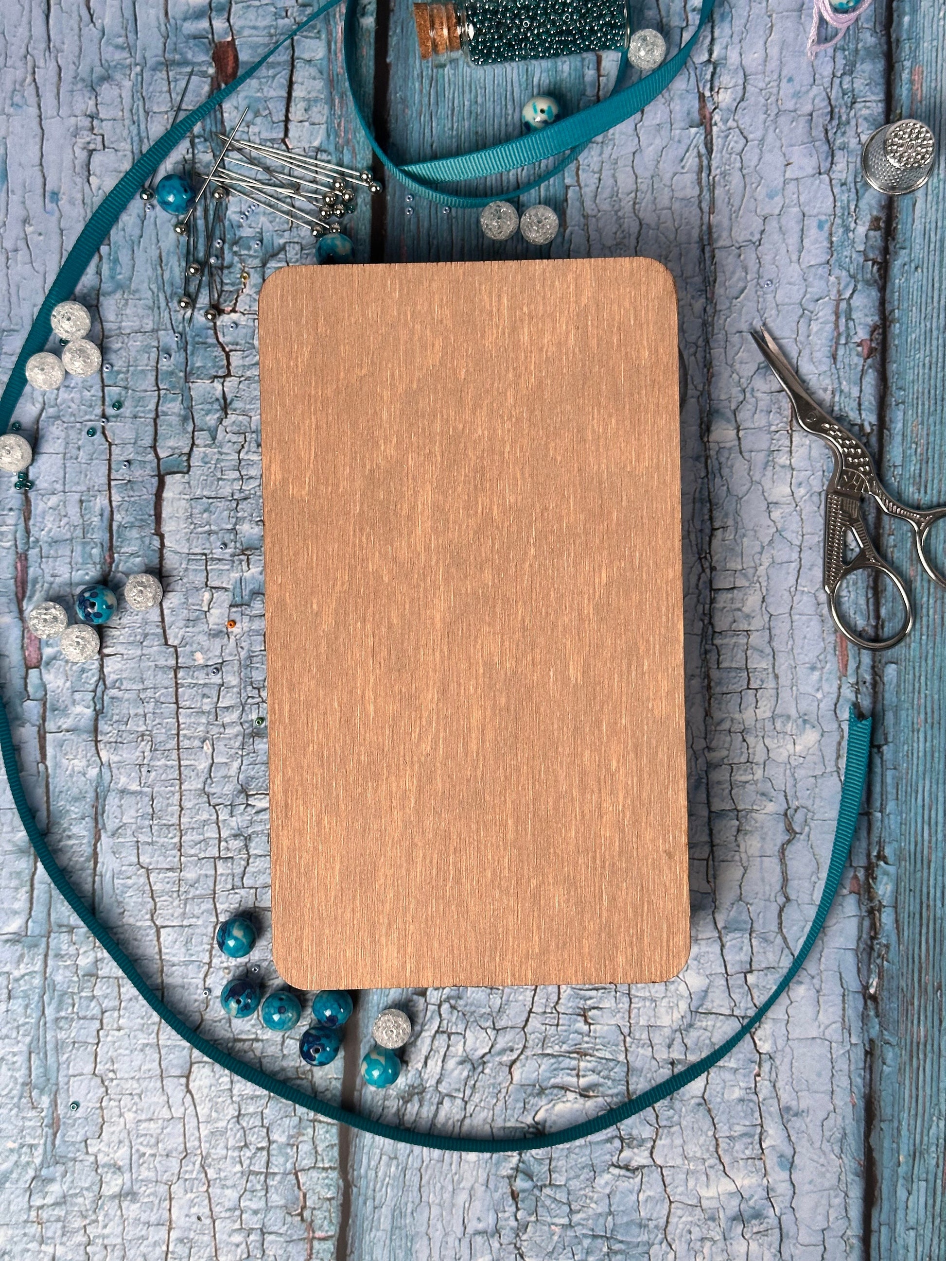 a wooden board surrounded by beads and a pair of scissors