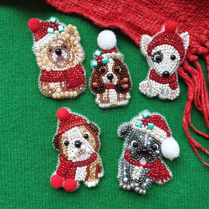 five beaded or embroidered dog or puppy brooches in various colors and styles, placed on a green background.