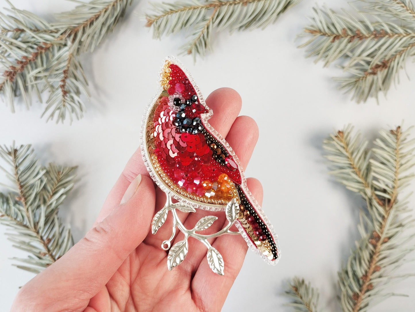 a hand holding a brooch with a bird on it