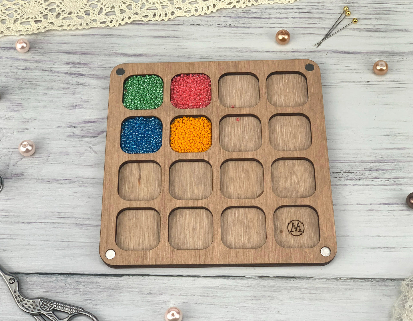 a wooden tray with beads and a pair of scissors