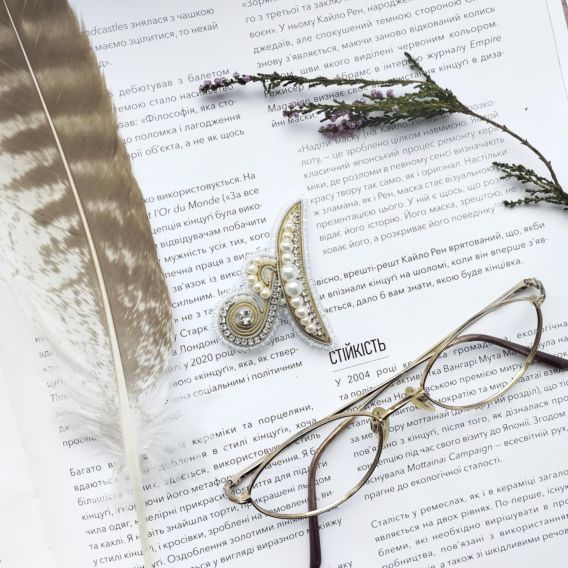 a close-up of a page with text in Russian, accompanied by a feather and a pair of glasses.