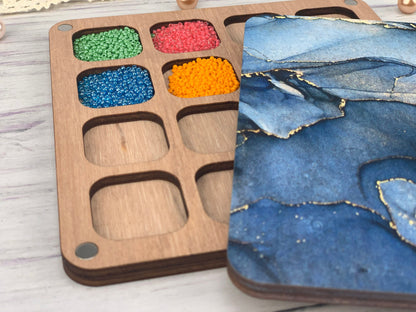 a wooden tray with different colored beads in it