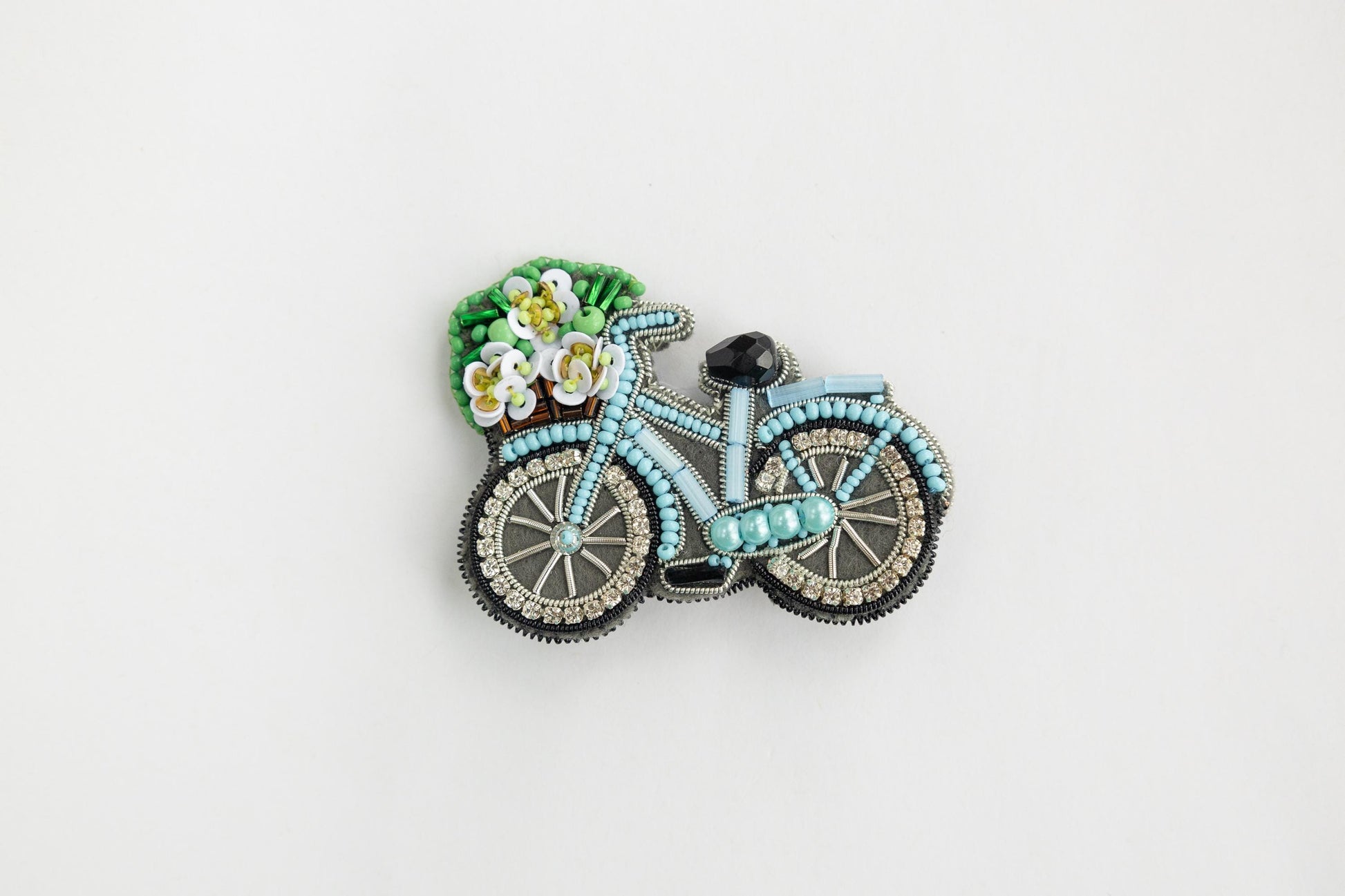 a brooch with a bicycle and flowers on it