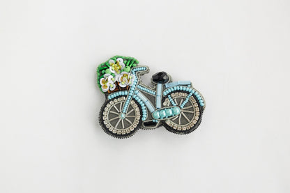 a brooch with a bicycle and flowers on it