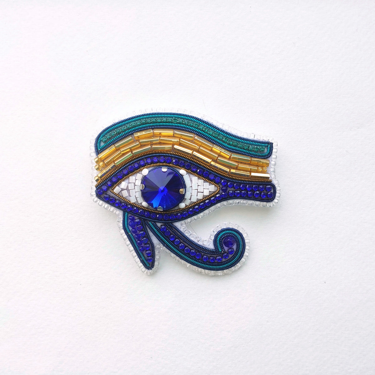 a decorative piece of jewelry, specifically a brooch or pin, with a large blue gemstone in the center. The piece is adorned with intricate patterns and designs, showcasing the craftsmanship and artistry involved in its creation.