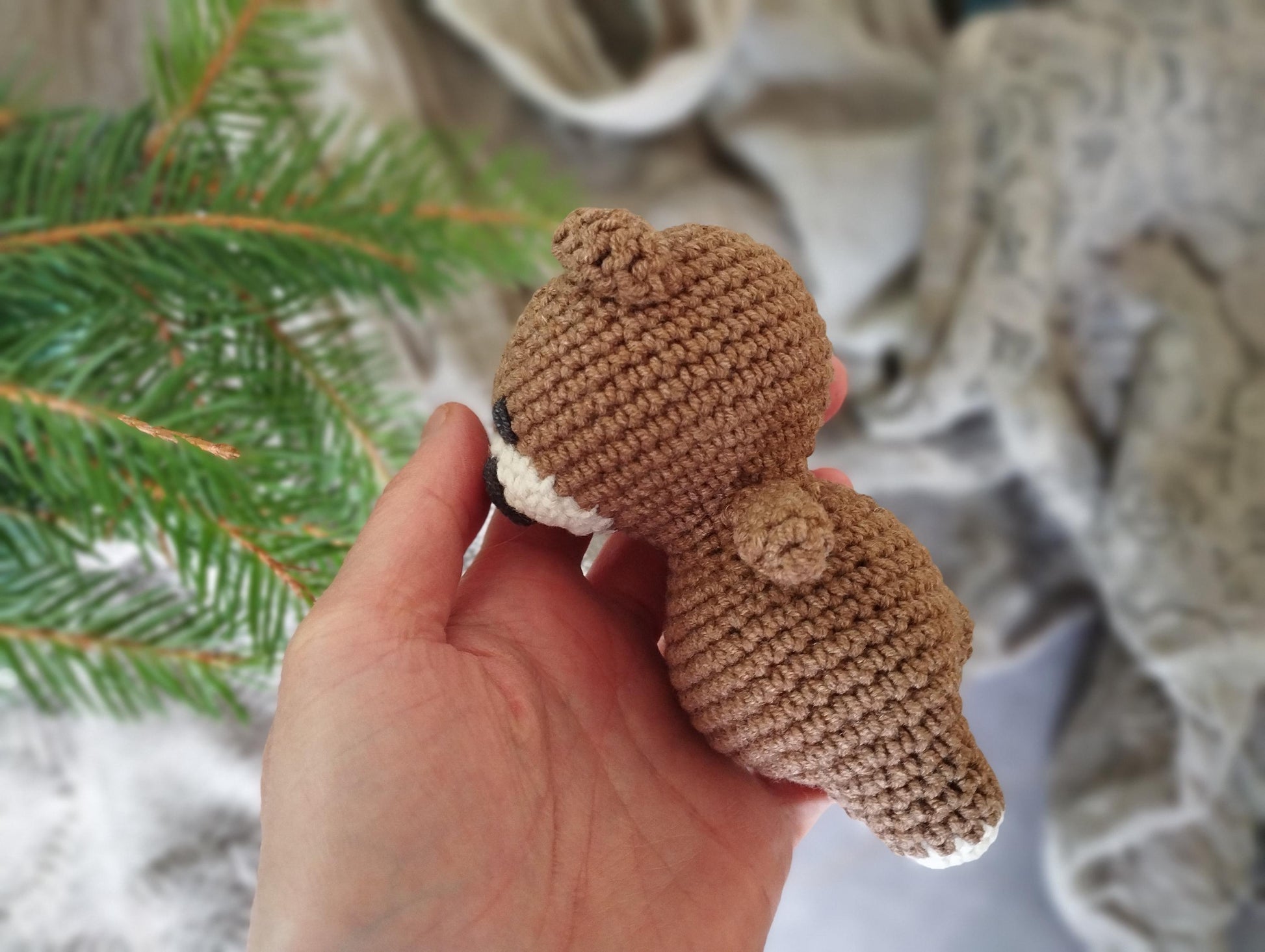 a hand holding a small crocheted teddy bear