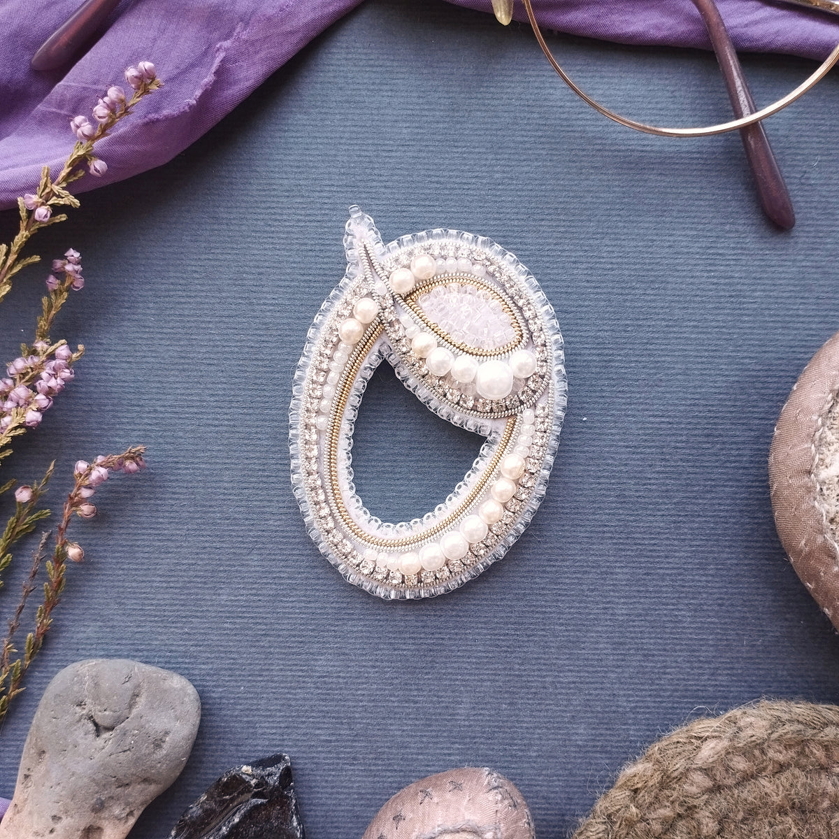 a close-up view of a decorative piece of jewelry, including a necklace and a brooch, placed on a textured surface.
