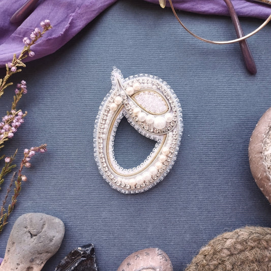 a close-up view of a decorative piece of jewelry, including a necklace and a brooch, placed on a textured surface.