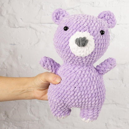 a purple knitted teddy bear standing on its hind legs