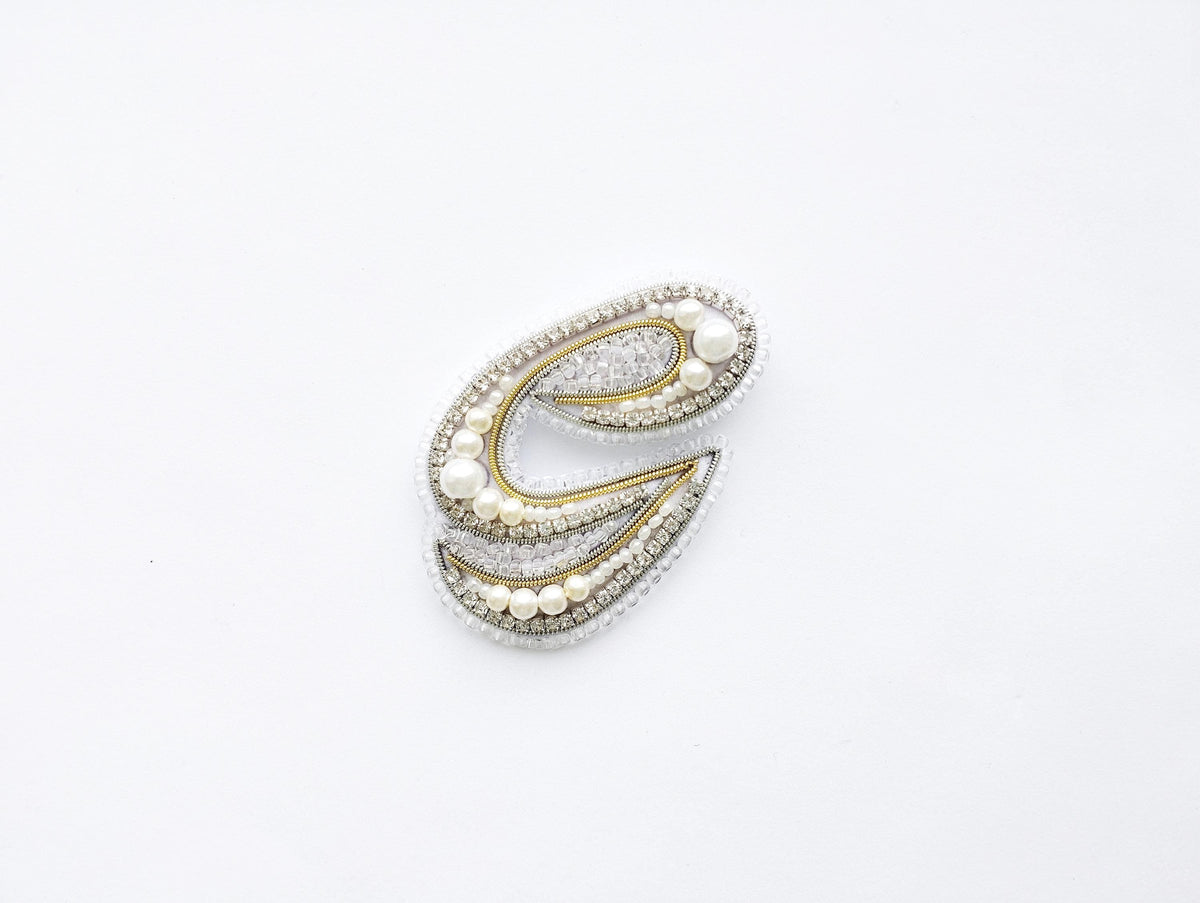 A decorative letter 'C' made of various materials, including pearls, diamonds, and other embellishments, against a white background.