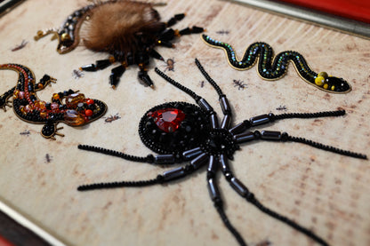 a close-up view of a detailed embroidered design on a surface, showcasing various insects and their intricate patterns.