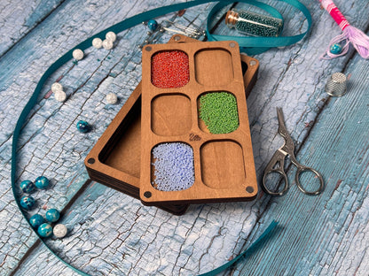 a wooden box with beads and a pair of scissors