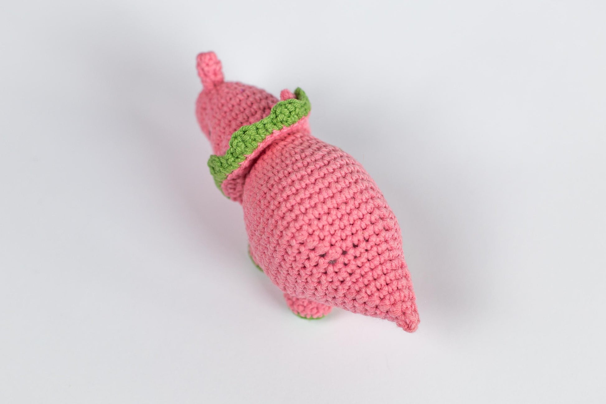 a crocheted pink toy with a green top