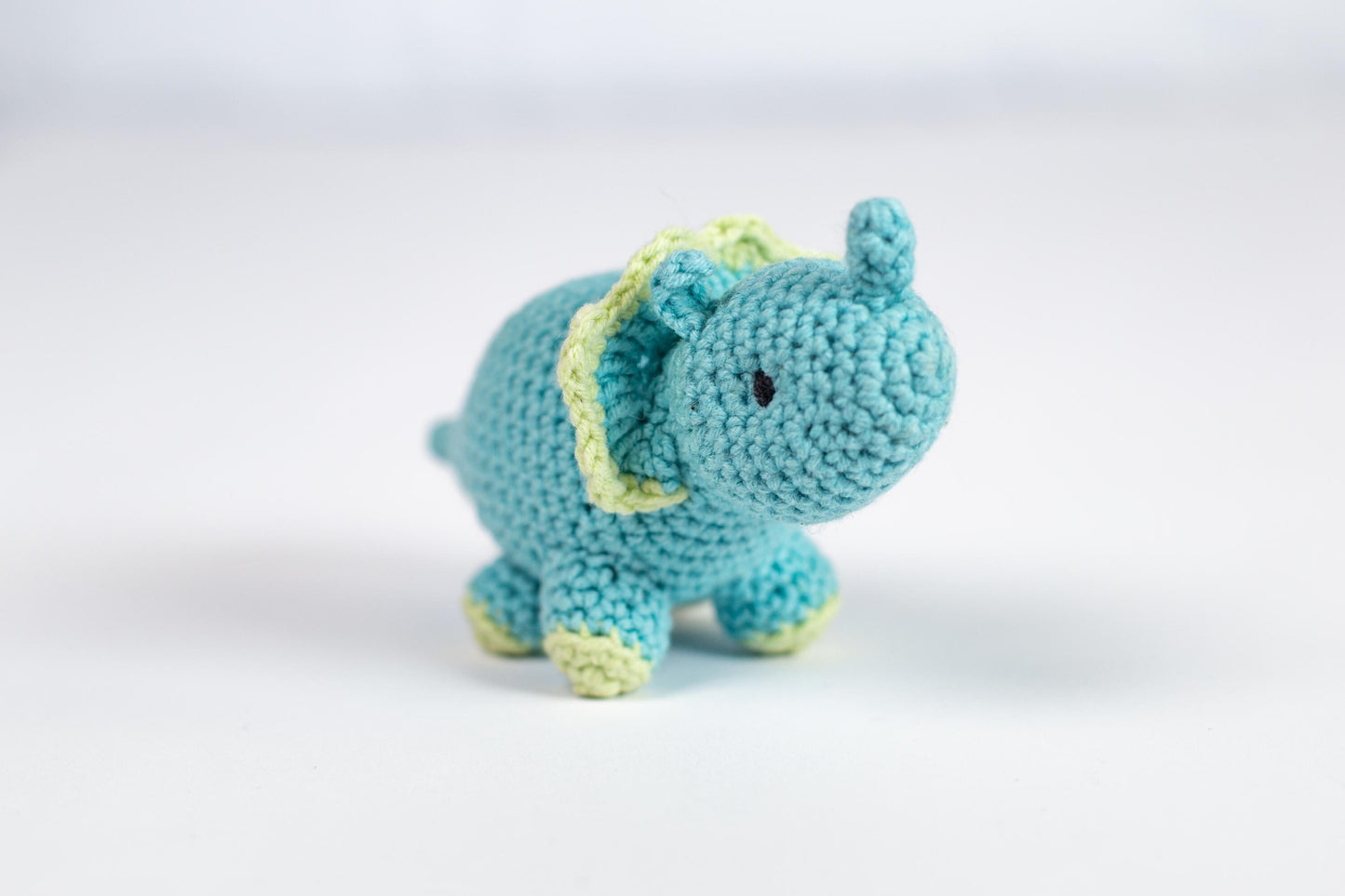 a small blue crocheted elephant sitting on a white surface