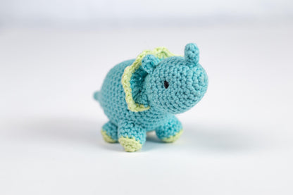 a small blue crocheted elephant sitting on a white surface